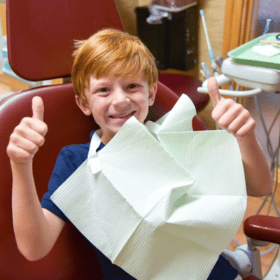 Young boy giving thumbs up at tidewater family dentistry, representing preventing childhood cavities